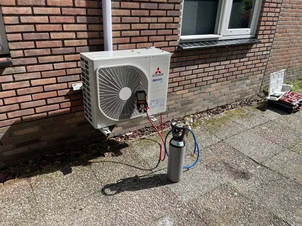 Buitenunit van een Mitsubishi Heavy Industries-airco op een muurbeugel aan de gevel in Een, tijdens de werkzaamheden