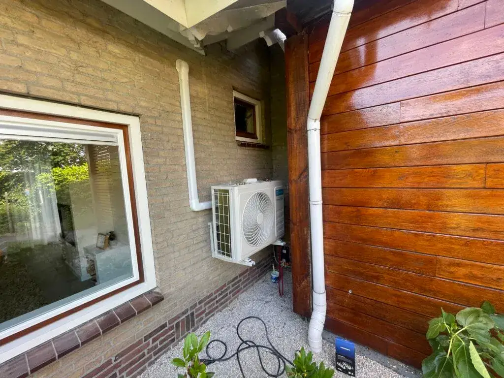 Buitenunit op een beugel aan de gevel bij de regenpijp, in Assen