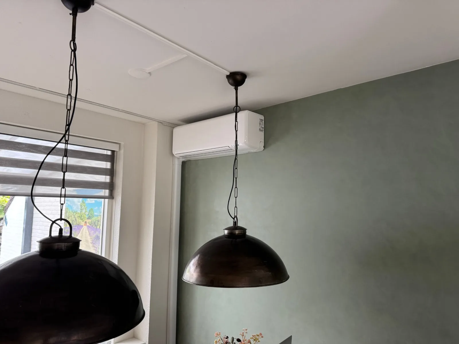 Witte Mitsubishi Heavy Industries-binnenunit hoog aan de wand in een woonkamer in Norg